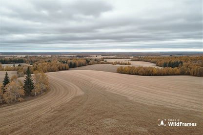 Elevated view of rolling harvested fields and autumn forest patches under a grey overcast sky, Finland